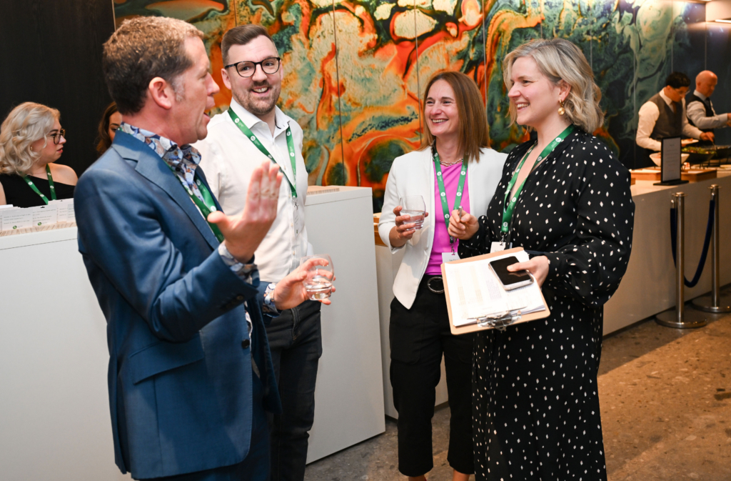 Four conference attendees chatting and smiling during a networking reception